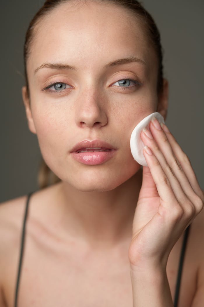 Contact Young woman using a cotton pad for skincare, highlighting beauty routine.